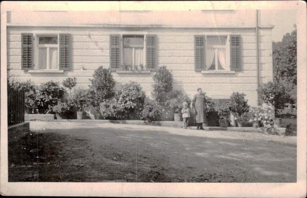 Frau und Kind vor Haus Vorderseite